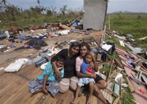 Sanjogeeta Kiran, right, with her sister Sulva Kiran, second left, and her children Shivendera, left, and Raajeen, sit amid the debris of their home in RakiRaki, Fiji, Wednesday, Feb. 24, 2016, after cyclone Winston ripped through the island nation. The cyclone tore through Fiji over the weekend with winds that reached 177 miles (285 kilometers) per hour, making it the strongest storm in Fiji's recorded history. (Brett Phibbs/New Zealand Herald via AP) 