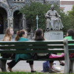 Statue of Georgetown University founder Carroll overlooks women on Georgetown campus in Washington